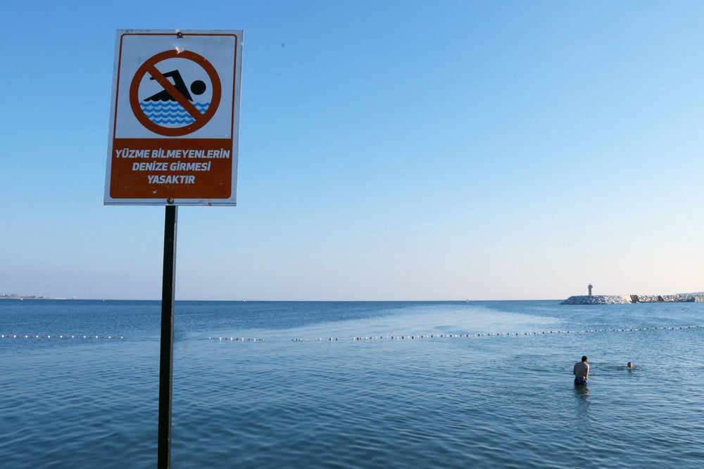 large red no swimming sign against blue water