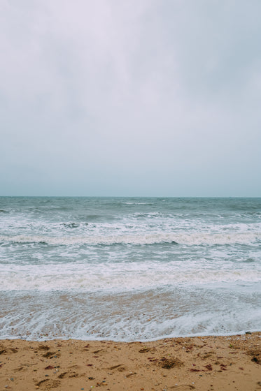 large waves lap the brown sandy shore