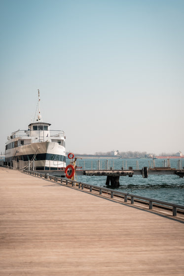 large white boat docked by a wooden boardwalk