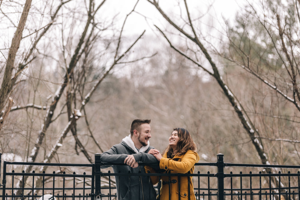 laughing couple leans against wrought iron fence