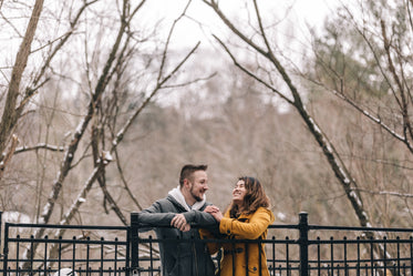 laughing couple leans against wrought iron fence