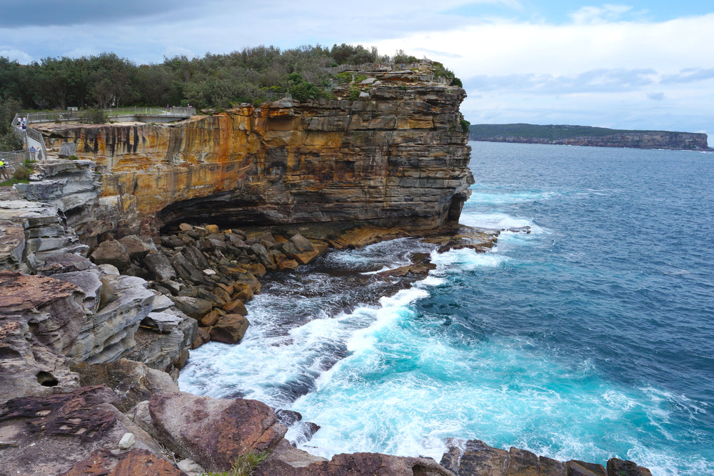 layers of rocky cliffs by crashing ocean waves