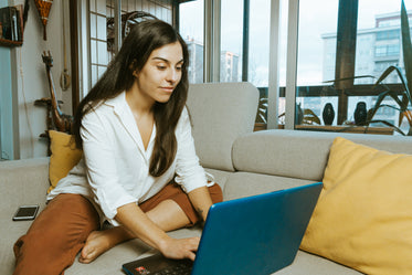 leaning forward to type on a laptop from couch