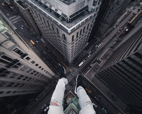 legs dangling over a heart-stopping drop to the city below