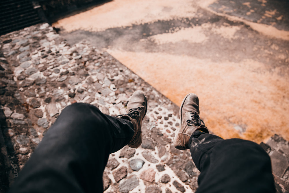 legs dangling over cobble stone road