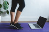 legs facing a open laptop on a yoga mat