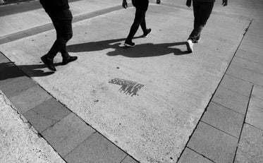 legs of three people walking in black and white