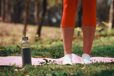 legs standing on a pink yoga mat outdoors