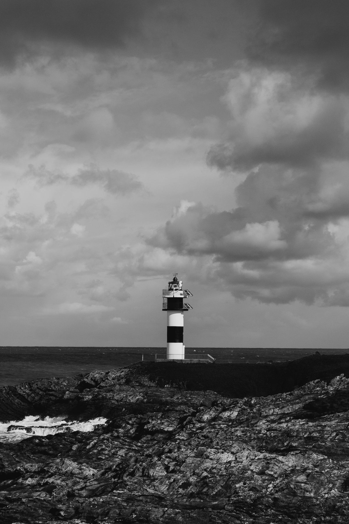 lighthouse on rocks overlooks water