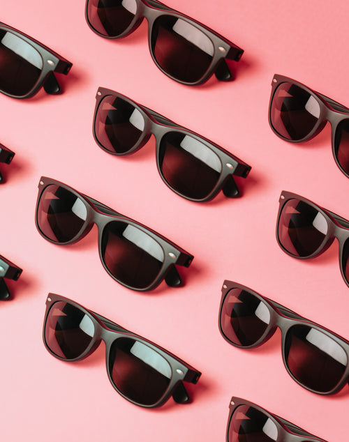 lined black sunglasses on a pink surface