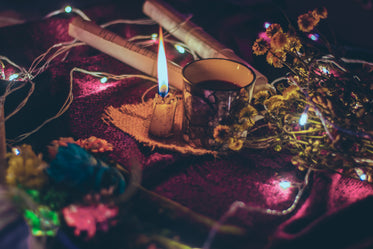 lit candle and black coffee surrounded by flowers