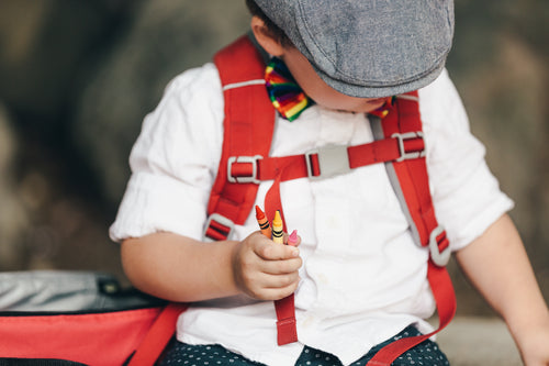 little boy in hat holding crayons