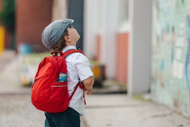 menino pronto para ir à escola olhando para cima