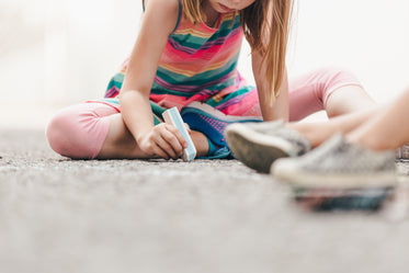 little girl drawing with chalk on ground