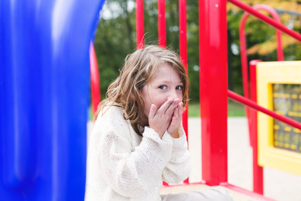 little girl laughing behind hands