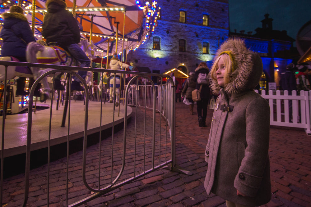 little girl watches winter fair ride