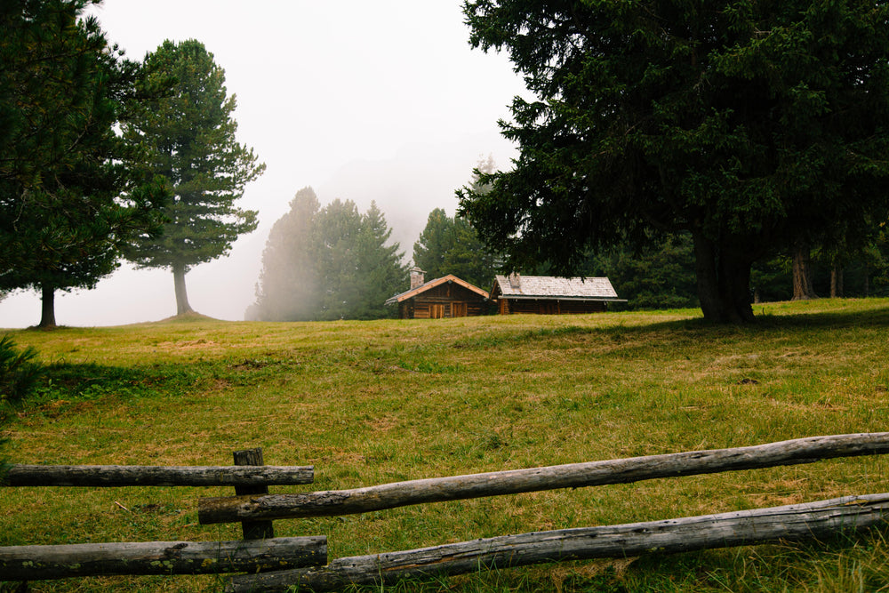 log cabin on a misty day surrounded by rail fence