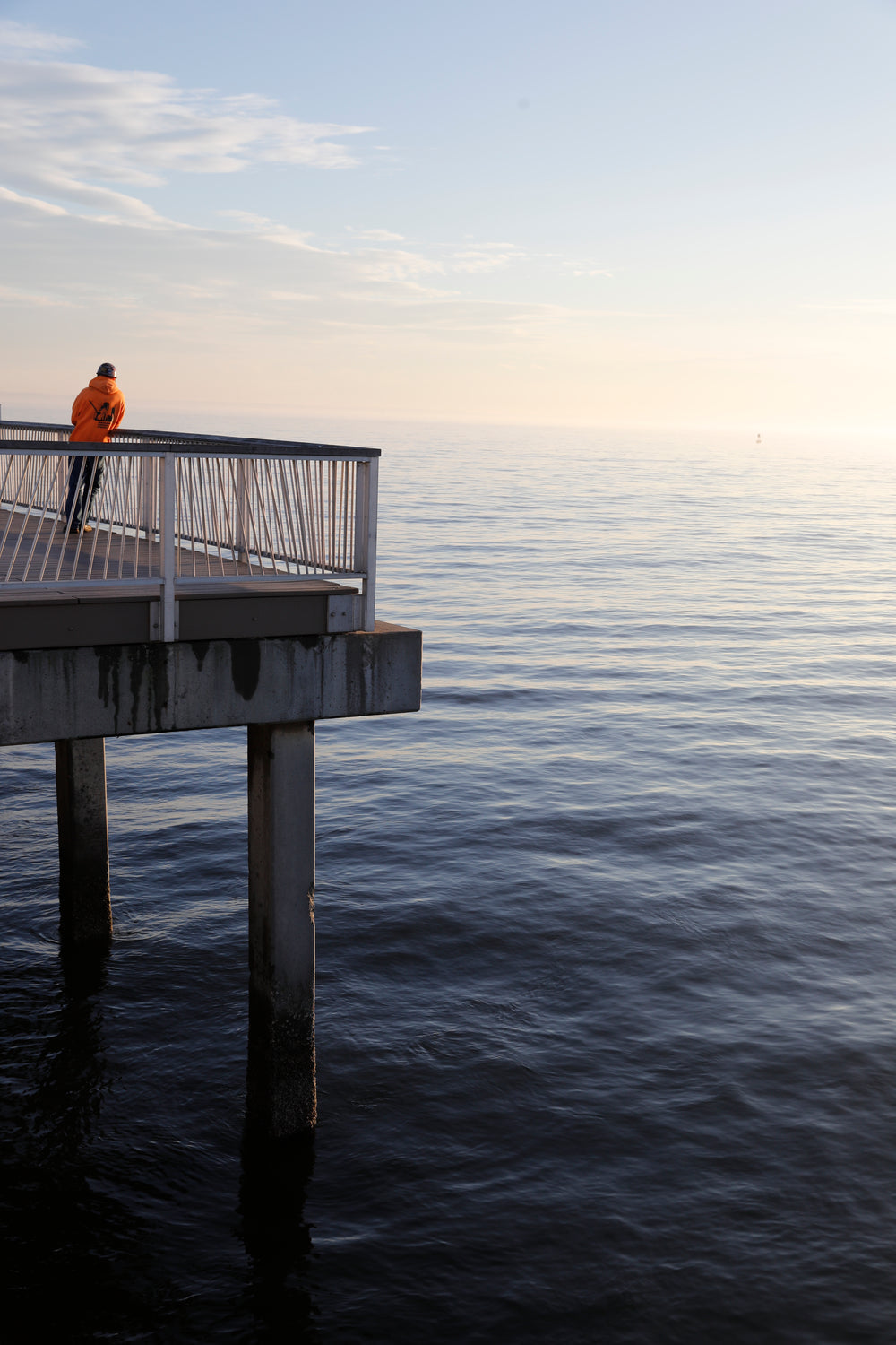 lone man stands on a pier at sunset