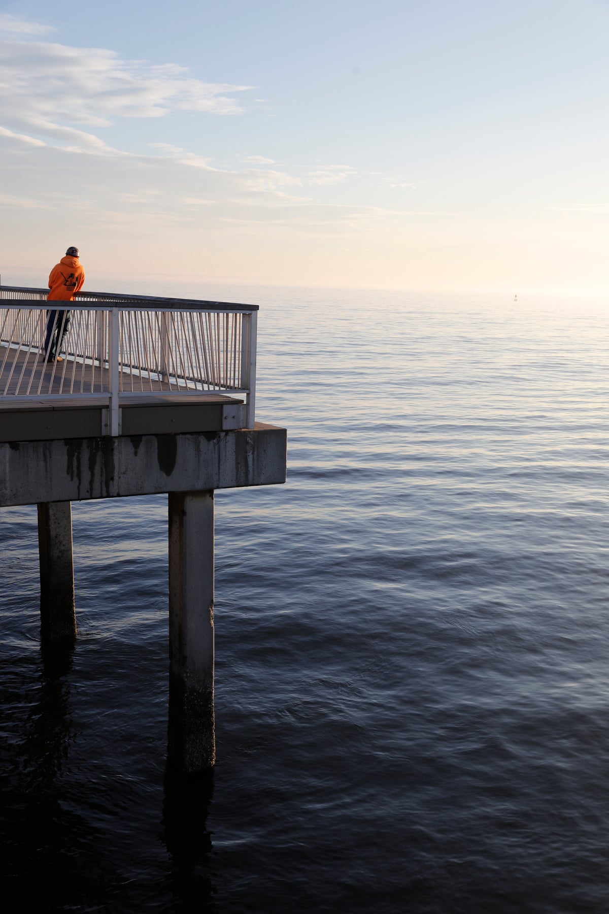 lone man stands on a pier at sunset