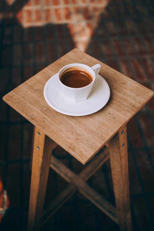 long espresso sits on a wooden stool
