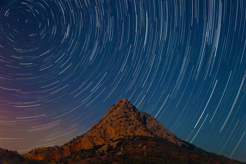 long exposure at night of streaking stars against landscape