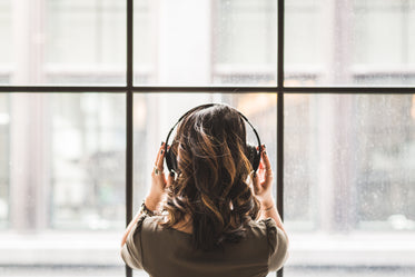 Picture of Looking Out Window Wearing Headphones - Free Stock Photo