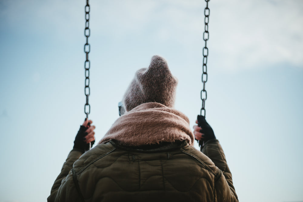 low view of young woman sat on swing