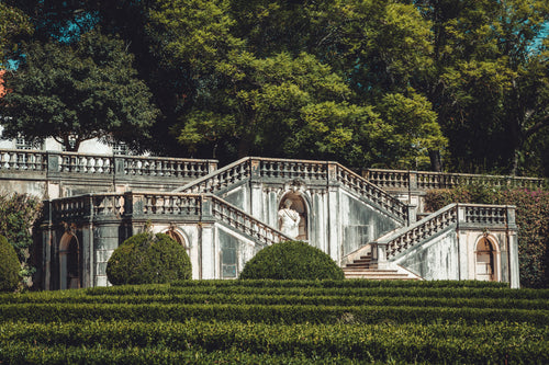lush green hedges surround carved marble stairs and statues
