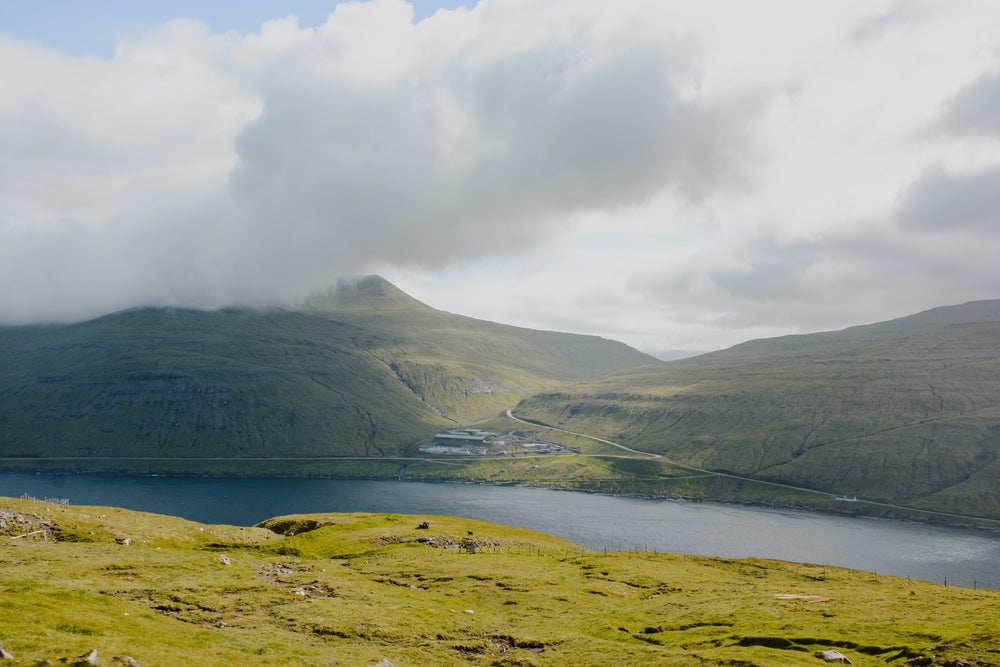 lush green rolling hills and waterway with misty clouds