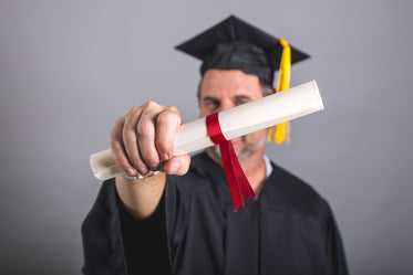 male grad student holding out diploma