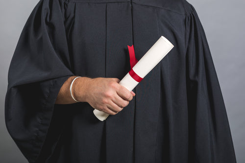 male student in gown holding diploma