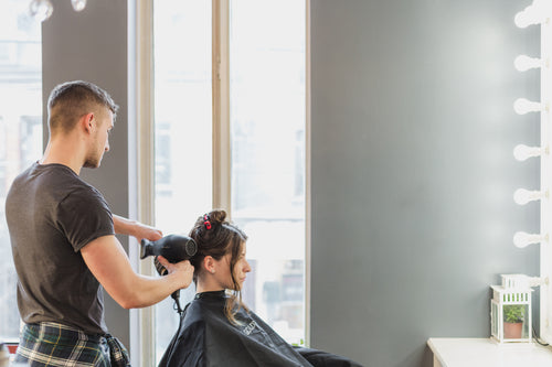 male stylist cutting hair at salon