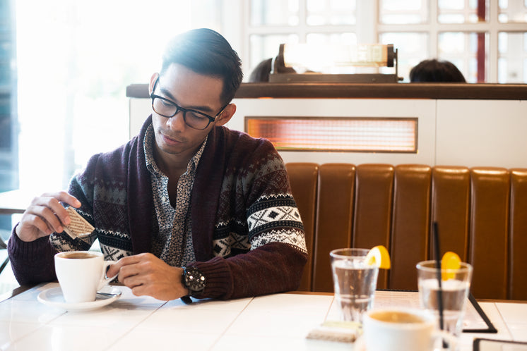 Man Adds Sugar To Coffee In Cafe