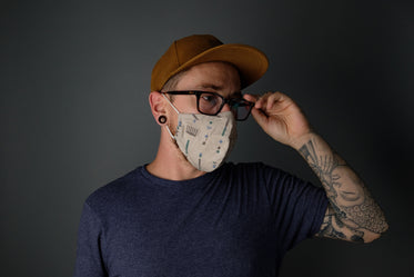 man adjusting his glasses while wearing mask