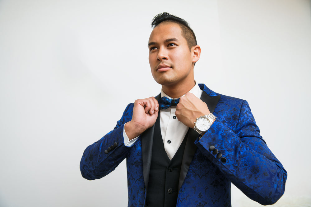 man adjusts blue tuxedo bowtie