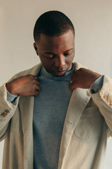 man adjusts the lapels on tan coat