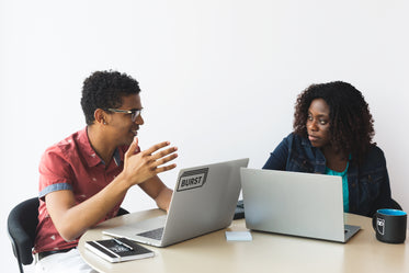 man and woman brainstorming with laptops