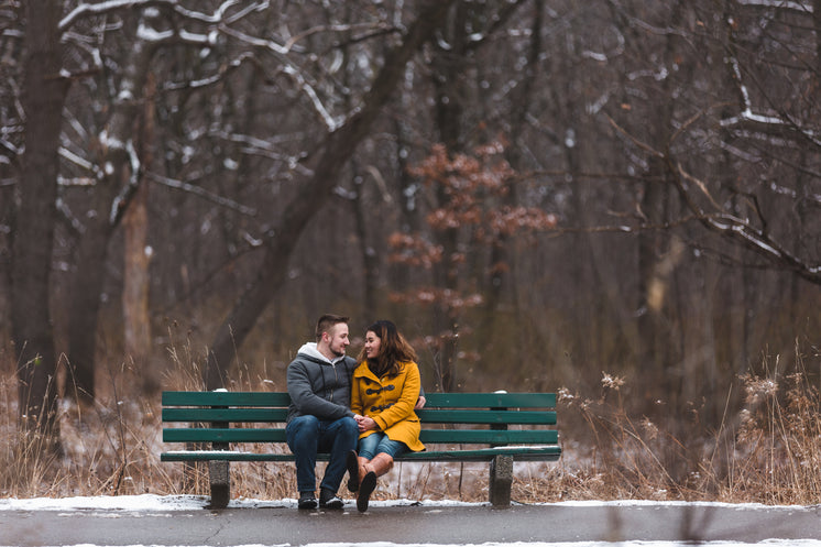 man-and-woman-hold-hands-on-a-bench-in-a