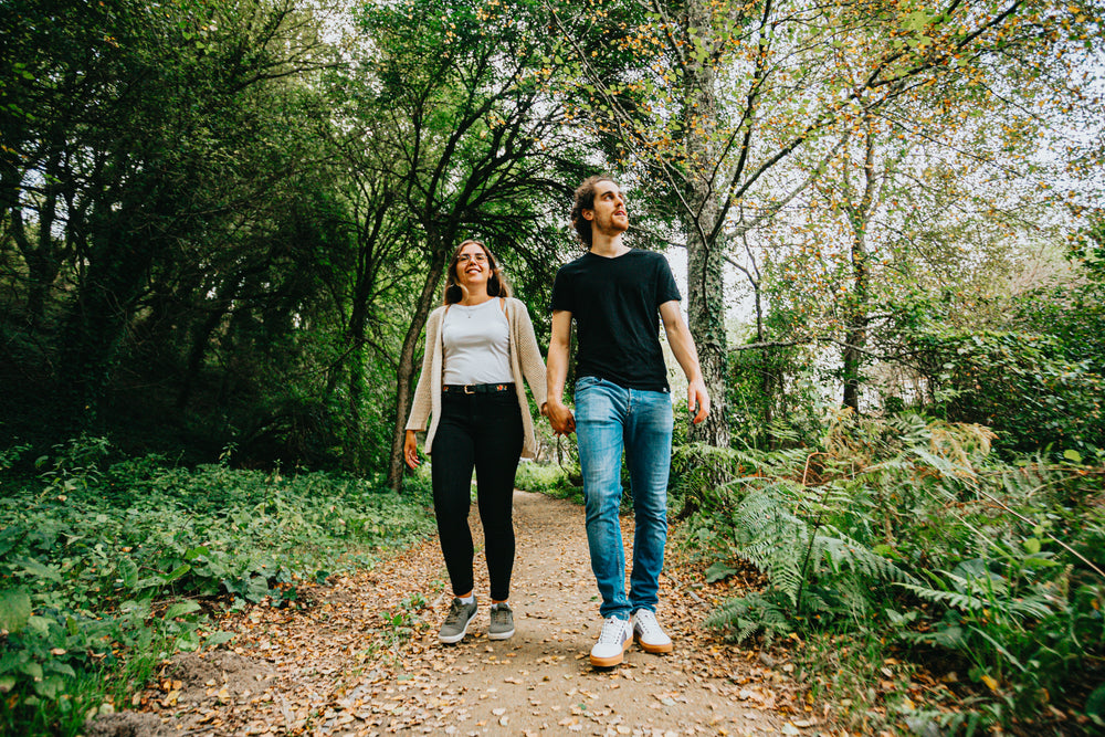 man and woman holding hands in a forest