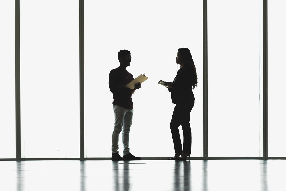 man and woman meeting in front of large windows