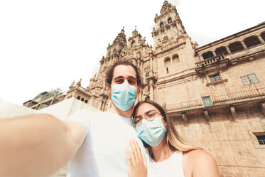 man and woman wear facemasks looking at the camera