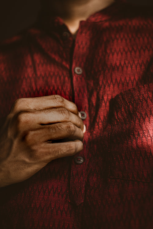 man buttoning a dark red shirt