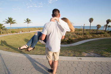 man carries woman in park