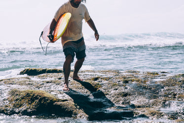 man carrying surfboard emerges from ocean waves