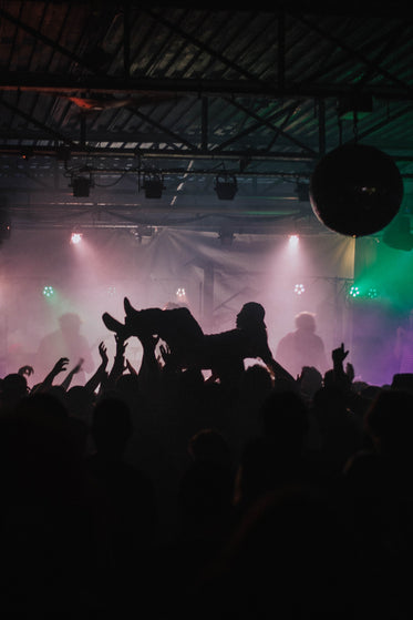 man crowd surfing in dark club