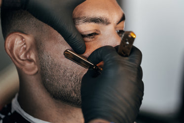 man gets his face shaved by a barber