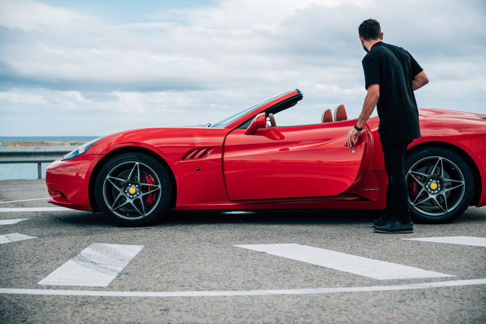 man getting into red sports car