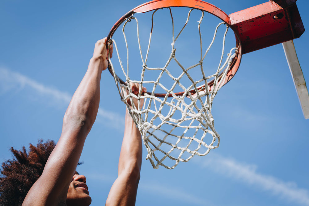 man hanging from basketball net