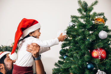 homem ajuda criança a decorar a árvore de natal