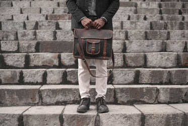 man holding a leather bag on a set of stairs